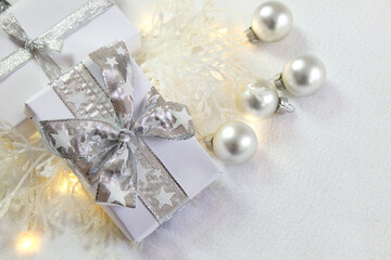 Bożonarodzeniowa srebrno-biała dekoracja z prezentami, bombkami i oszronionymi gałązkami  © Monika