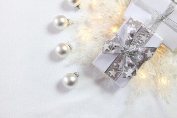 Bożonarodzeniowa srebrno-biała dekoracja z prezentami, bombkami i oszronionymi gałązkami
