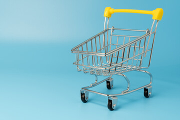 Empty shopping cart with yellow handle on blue background. Shopping concept.