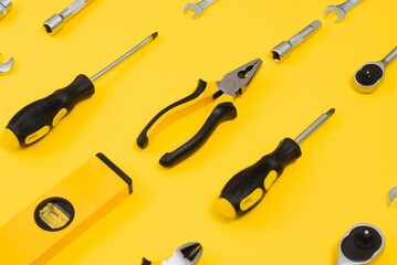 Yellow and black handy tools (pilers and screwdriver) isolated on yellow background