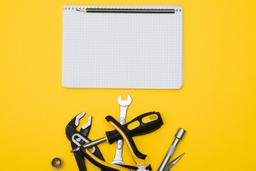 Tools top view on yellow background. Plier, open wrenches, screwdrivers and staple gun flat lay with copy space.