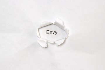 Word envy on white isolated background through the wound hole in the paper.