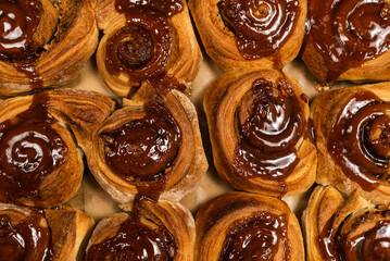 Homemade cinnamon buns with spices and caramel on parchment paper.