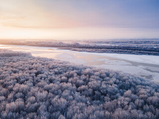 winter forest view with partially frozen river in the back at sunset