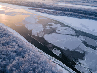 Bird's eye view of the river passing through a forest partially covered with ice.