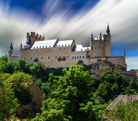 Fototapeta na wymiar Castle of Segovia on top of the mountain with green vegetation and blue sky. 
