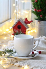 coffee in a white cup on the background of Christmas garland and spruce