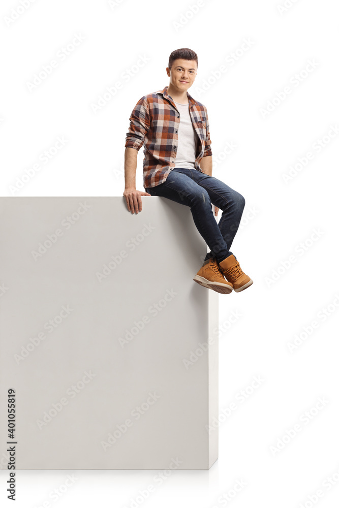 Wall mural Guy sitting on a high wall and smiling at camera