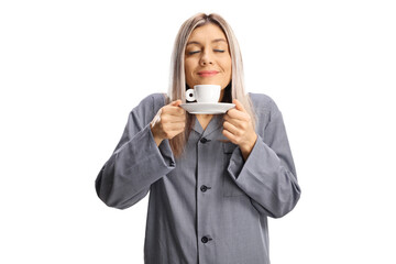 Young woman in pajamas smelling a cup of espresso coffee