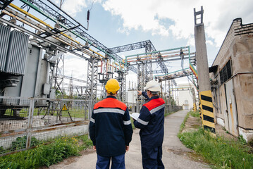 Two specialist electrical substation engineers inspect modern high-voltage equipment. Energy. Industry