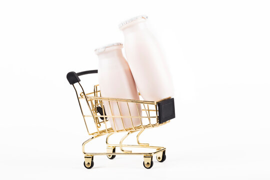 On white background. Children's shopping cart yellow. It contains a white plastic bottle. No isolation