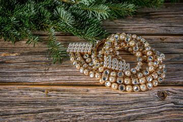 Top view Christmas background with belt of gold, crystal white stones and pearls . Fir tree on wooden table with copy space.