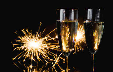 Two glasses of champagne with sparklers in background. New Year's Eve celebration.