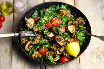 Warm salad with eggplant and spinach in a skillet. Healthy food. Vegan lunch.