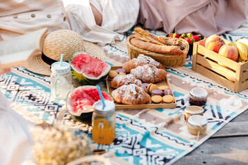 Picnic at the park. Fresh fruits, ice cold sparkling drinks and croissants on a hot summer day. Picnic lunch. selective focus