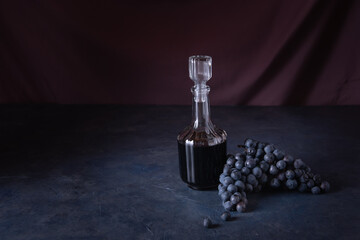 balsamic vinegar in a glass bottle with a bunch of grapes on a stone table
