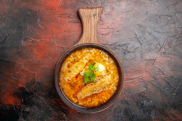 top view chicken soup in wood bowl with handle on dark red background with copy space