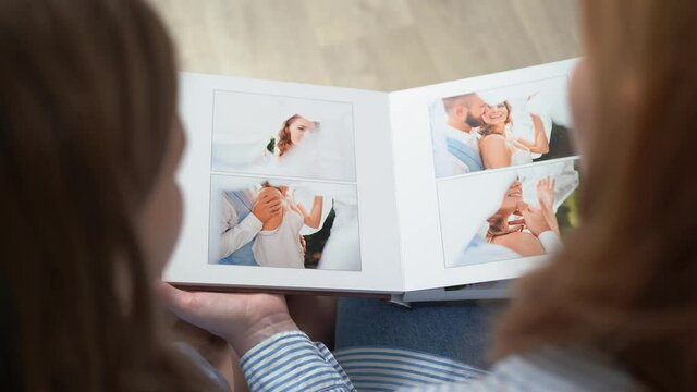 top view. mom and daughter leaf through the wedding photobook.