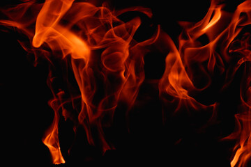 Fototapeta premium Abstract fire flame in fireplace, texture for background. Beautiful bright orange flames flicker in the darkness of the night.