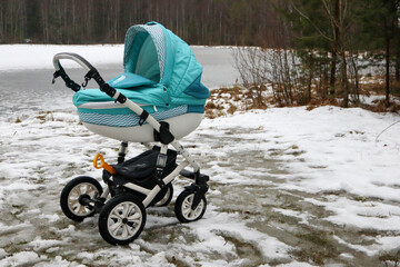 colorful baby carriage in the park with frozen lake on the background