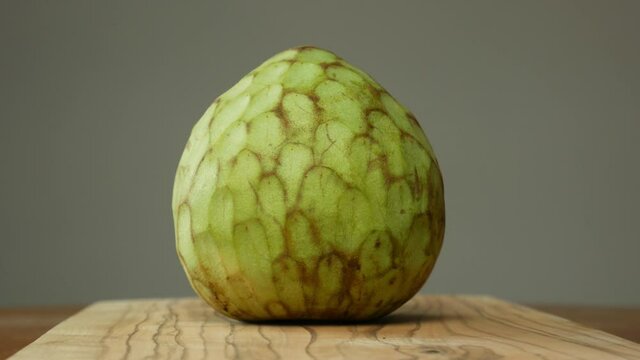 Cherimoya fruit, Graviola ripe on wooden cutting board, while slow rotation video, custard apple on chopping board