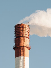 Working chimney above the city on a blue clean sky