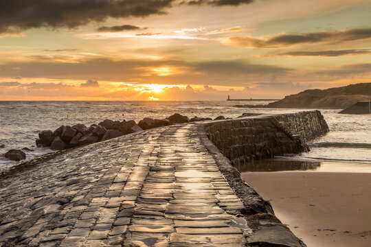 Sunrise at a chilly Cullercoats Bay in the north east of England, with Tynemouth Pier and the lighthouse in the distance