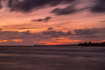 Obraz na płótnie Canvas Sunrise at a chilly Cullercoats Bay in the north east of England, with Tynemouth Pier and the lighthouse in the distance