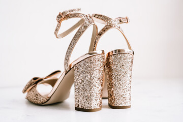 Golden womens shoes with heels and sequins on white background. 