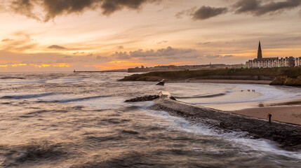 Sunrise at a chilly Cullercoats Bay in the north east of England, with Tynemouth Pier and the lighthouse in the distance