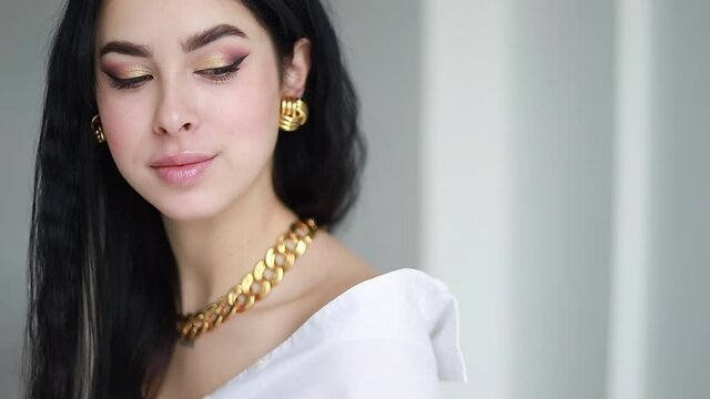 Luxury fashionable girl puts on gold jewelry around her neck. Trying on a gold chain around the neck. Jewelry advertising. Gold thick chain.