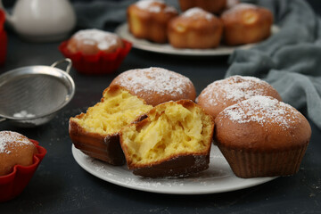 Homemade muffins with pineapple pieces, sprinkled with powdered sugar, arranged on a dark background. Closeup. Horizontal format