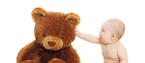 Portrait of little baby sitting on the floor playing with big teddy bear toy on a white background