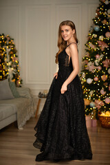 Beautiful elegant woman in black evening dress over christmas tree