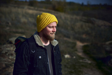 A young tourist in yellow hat and a backpack standind on mountain's walkway background. Travel, Adventure, nature,Freedom concept.