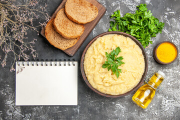 top view mashed potatoes bread slices on cutting board parsley oil turmeric a notebook on dark background