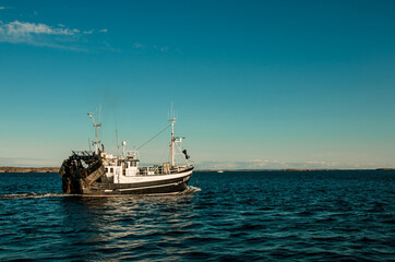 Obraz premium Fishing boat leaving harbour in calm seas
