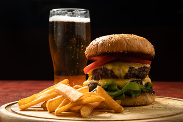 fast food with beer on the table, fries and burger on a wooden board.