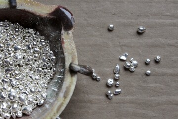 A ceramic crucible or melting pot with grains of sterling silver 925 for jewelry making after hand smelting in a workshop. One of the two major precious metals on the market.