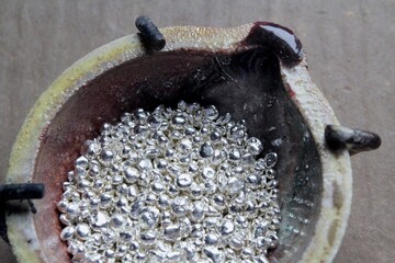 A ceramic crucible or melting pot with grains of sterling silver 925 for jewelry making after hand smelting in a workshop. One of the two major precious metals on the market.