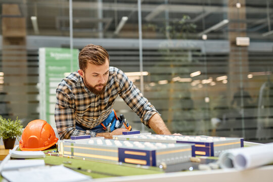 young student architect working on architectural project concept, using 3d model layout, university student is planning engineering design, brainstorming at workplace alone