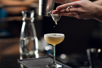 An experienced bartender prepares an alcoholic cocktail. No face, close-up, copy space