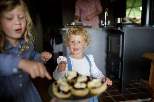 Cute girls reaching for biscuits with jelly and cream