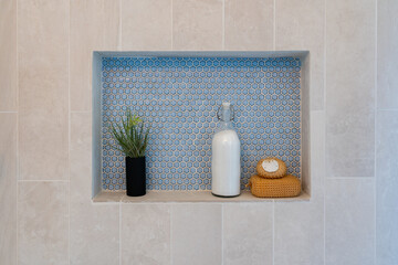 Detail of tile and stone shower inset with bath salts, loofah, and plant decor.