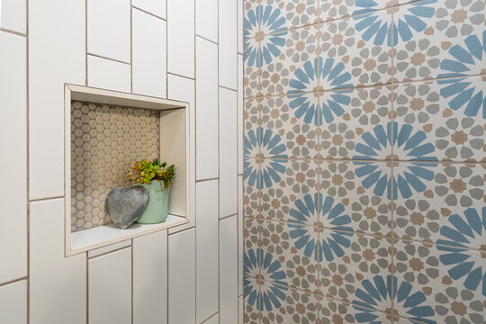 Detail of flower pattern tile shower inset with heart and plant decor.