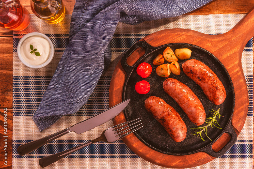 Wall mural Pork sausage roasted in an iron frying pan - Top view