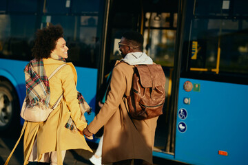 Happy black couple holding hands while walking at bus station.