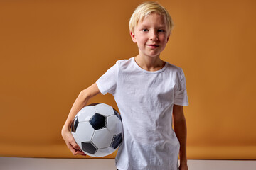 football player with ball isolated in studio, posing at camera, wearing football uniform, white t-shirt. sport, soccer concept