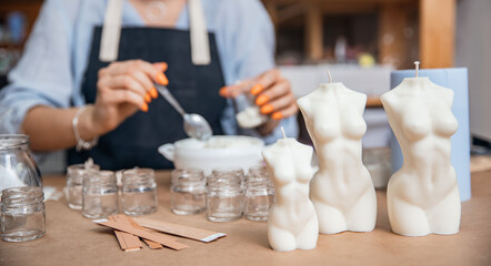 Young woman workplace in production of aromatic wax candles in shape of female Venus body in art studio. Concept craftswoman startup