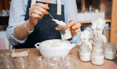 Concept craftswoman small business. Young woman workplace is engaged in production of aromatic wax candles in shape of female Venus body